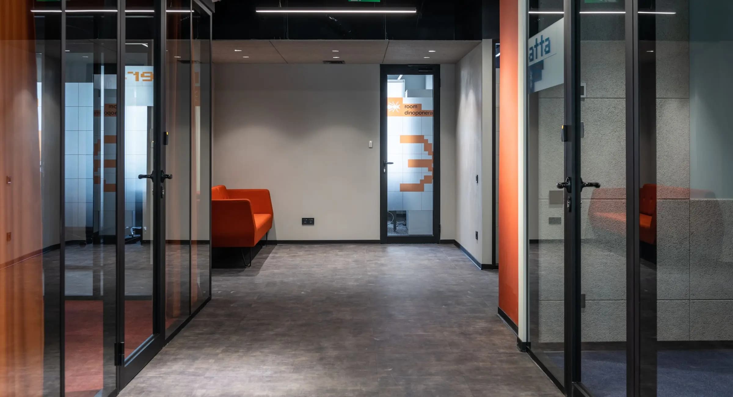 Office corridor opening onto glass-walled meeting rooms